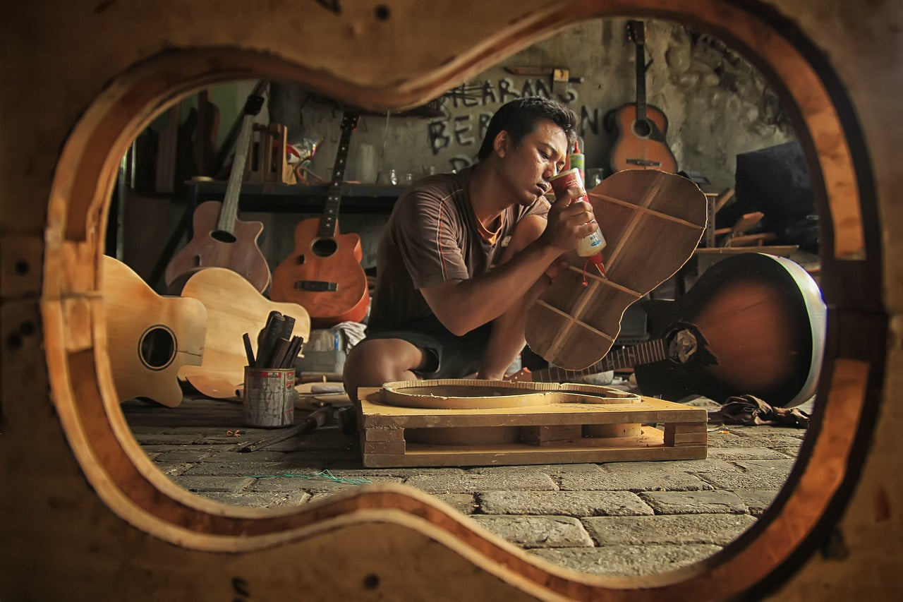 A man builds a guitar in his workshop.