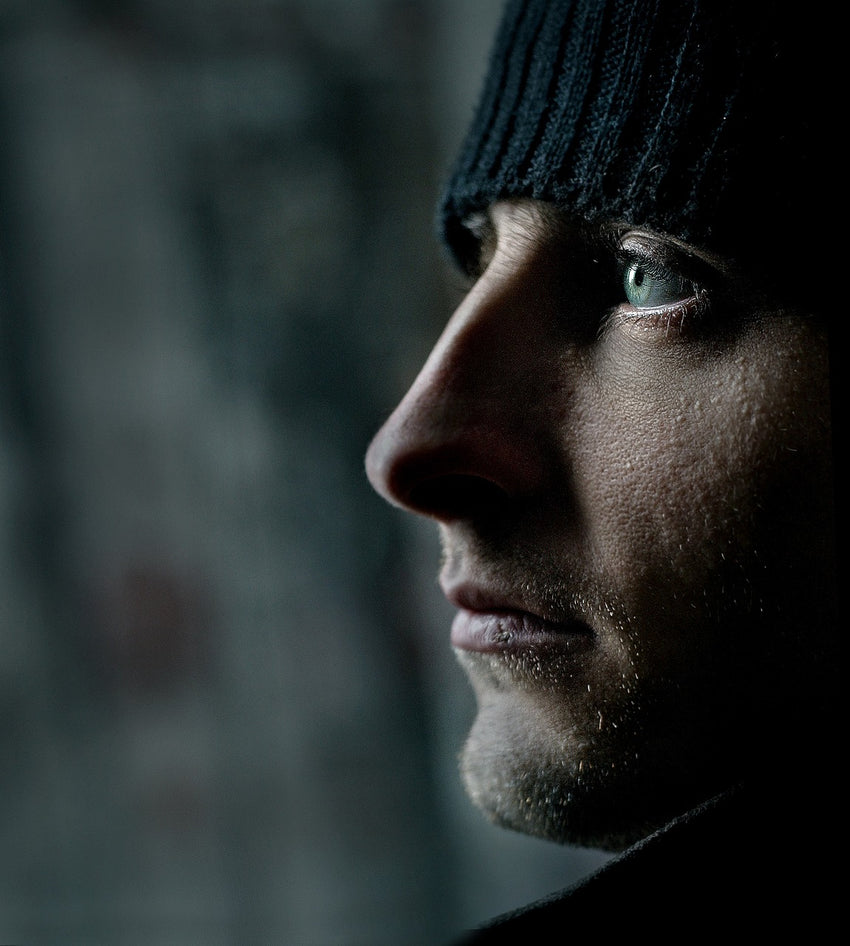 A man in dark clothing stares into the distance.