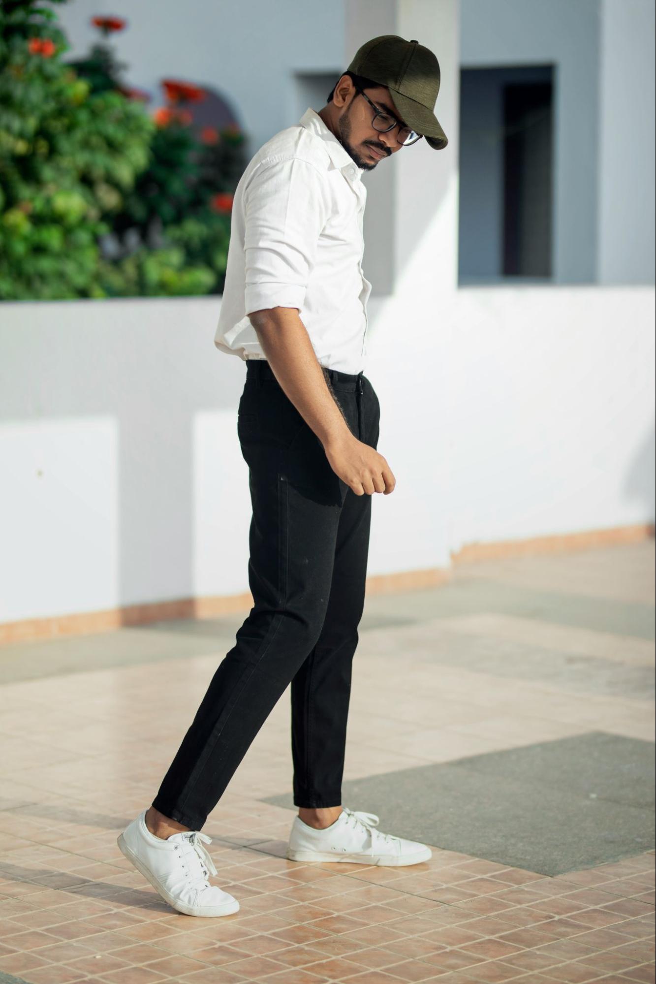 A man wearing chinos, a white shirt, and a green cap outside.